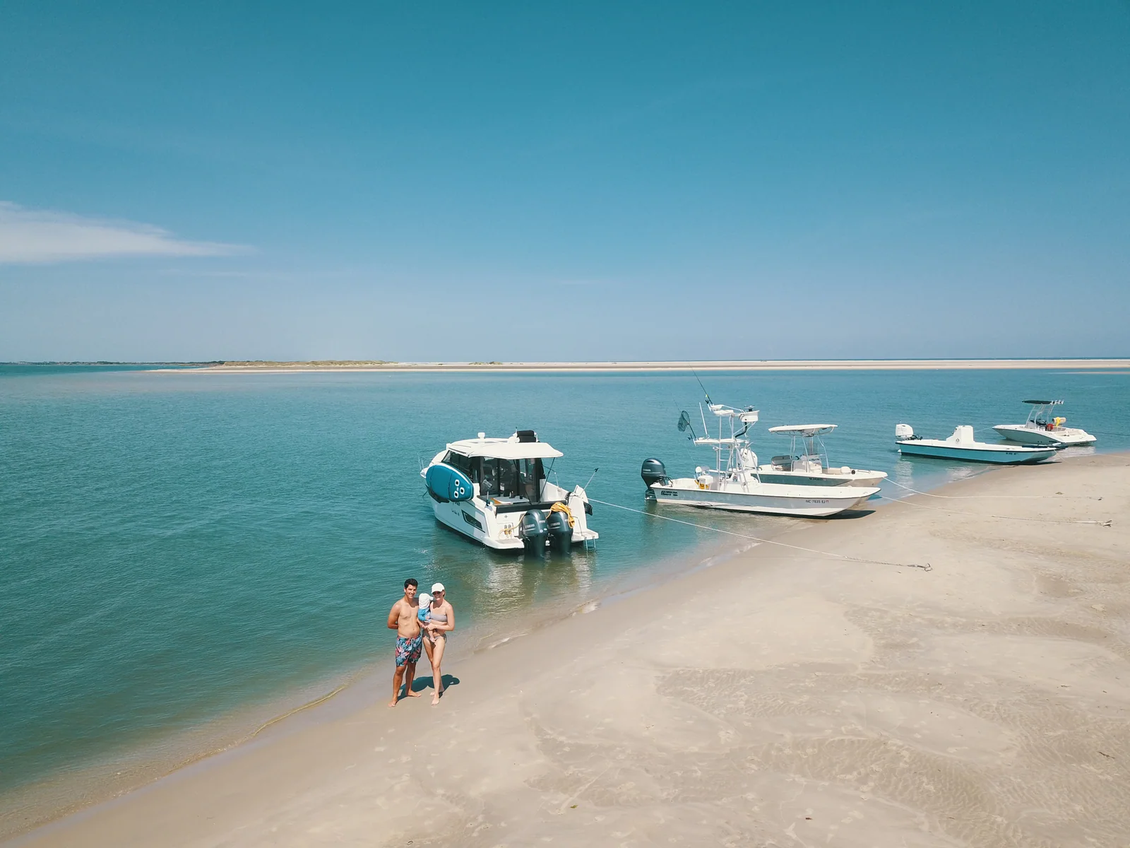 EZ Livin anchored by a beach with other boats and people at the shoreline