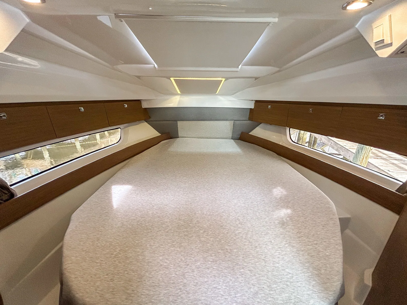 Forward private cabin with double berth, hull windows and wood storage lockers